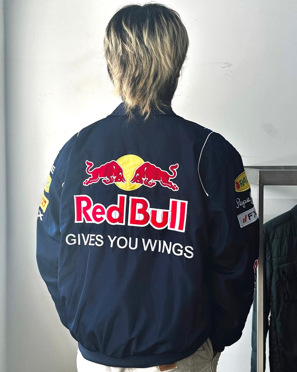 Model showcasing a stylish Red Bull Racing jacket, perfect for racing events and casual wear, highlighting the team’s branding