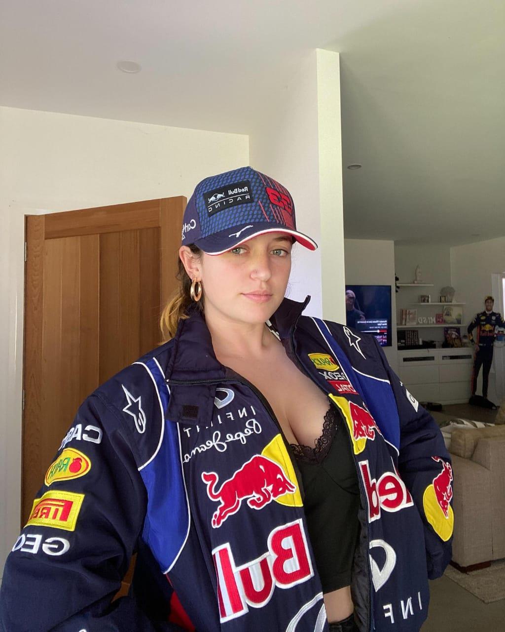 Close-up profile of the front zipper, high-density Red Bull racing sponsor badges, and contrast parachute fabric paneling on the chest of the navy blue motorsport jacket.